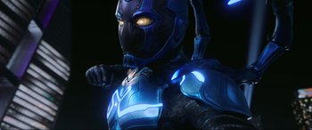 Movie still from “Blue Beetle” (2023), directed by Angel Manuel Soto – A person wearing a blue suit; Medium shot, Low angle
