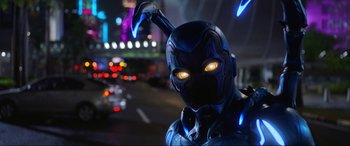 Movie still from “Blue Beetle” (2023), directed by Angel Manuel Soto – A man in a blue suit with yellow glowing eyes; Close Up shot, Low angle