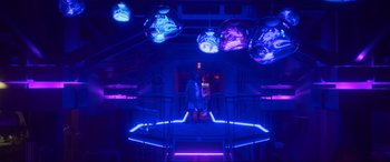 Movie still from “Blue Beetle” (2023), directed by Angel Manuel Soto – Two people standing in a room lit up with neon lights; Wide shot, Low angle