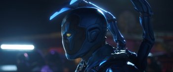 Movie still from “Blue Beetle” (2023), directed by Angel Manuel Soto – A person wearing a blue helmet; Close Up shot, Low angle