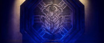 Movie still from “Blue Beetle” (2023), directed by Angel Manuel Soto – A wall decoration with a face carved into it; Extreme Close Up shot, Overhead angle