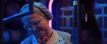 Movie still from “Blue Beetle” (2023), directed by Angel Manuel Soto – A woman with glasses is listening to music; Close Up shot, Over the shoulder angle