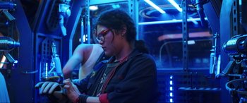 Movie still from “Blue Beetle” (2023), directed by Angel Manuel Soto – A young woman in glasses looking at her cell phone; Medium shot, Low angle