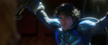 Movie still from “Blue Beetle” (2023), directed by Angel Manuel Soto – A man in a blue and black suit holding a sword; Close Up shot, Over the shoulder angle