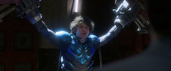 Movie still from “Blue Beetle” (2023), directed by Angel Manuel Soto – A young man in a blue suit holding a sword; Medium shot, Low angle