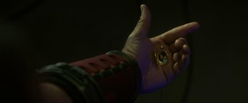 Movie still from “Blue Beetle” (2023), directed by Angel Manuel Soto – A hand is holding up a small gold locket; Extreme Close Up shot, High angle