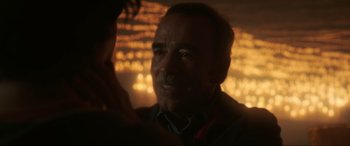 Movie still from “Blue Beetle” (2023), directed by Angel Manuel Soto – An older man is looking at the camera; Close Up shot, Over the shoulder angle