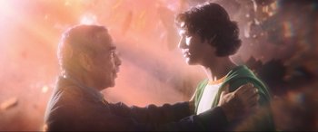 Movie still from “Blue Beetle” (2023), directed by Angel Manuel Soto – Two men are touching each other's heads in the sunlight; Medium shot, Low angle