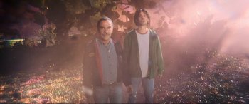 Movie still from “Blue Beetle” (2023), directed by Angel Manuel Soto – A man and a young boy standing next to each other; Medium shot, Low angle