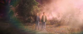 Movie still from “Blue Beetle” (2023), directed by Angel Manuel Soto – Two people standing in front of a smoke filled sky; Wide shot, Low angle