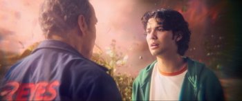 Movie still from “Blue Beetle” (2023), directed by Angel Manuel Soto – A man standing next to another man in front of flowers; Close Up shot, Over the shoulder angle