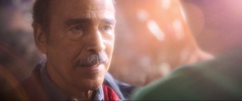 Movie still from “Blue Beetle” (2023), directed by Angel Manuel Soto – An older man with a mustache is looking at the camera; Extreme Close Up shot, Over the shoulder angle