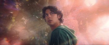 Movie still from “Blue Beetle” (2023), directed by Angel Manuel Soto – A young man in a green hoodie looking up at the sky; Close Up shot, Low angle