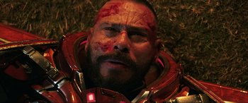 Movie still from “Blue Beetle” (2023), directed by Angel Manuel Soto – A person wearing a helmet with blood on his face; Close Up shot, Overhead angle