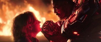 Movie still from “Blue Beetle” (2023), directed by Angel Manuel Soto – A man and a boy face each other in front of a fire background; Close Up shot, Low angle