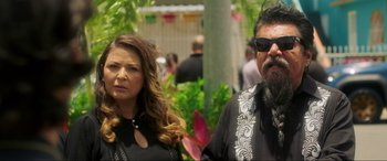 Movie still from “Blue Beetle” (2023), directed by Angel Manuel Soto – A man and a woman standing next to each other in front of trees; Close Up shot, Over the shoulder angle