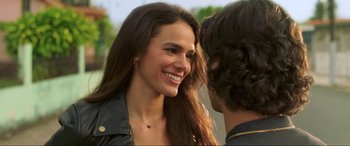 Movie still from “Blue Beetle” (2023), directed by Angel Manuel Soto – A woman smiling at a man in a leather jacket; Close Up shot, Over the shoulder angle