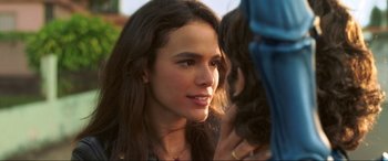 Movie still from “Blue Beetle” (2023), directed by Angel Manuel Soto – A young woman with long dark brown hair looking at the camera; Close Up shot, Over the shoulder angle