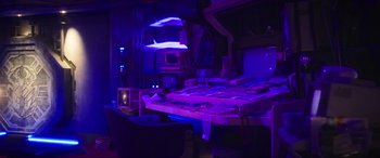 Movie still from “Blue Beetle” (2023), directed by Angel Manuel Soto – A room that has a lot of purple lights in it; Wide shot, Low angle