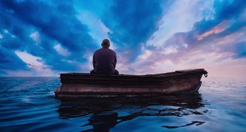 Movie still from “Blue Miracle” (2021), directed by Julio Quintana – A man sitting in a boat on a body of water; Wide shot, Low angle