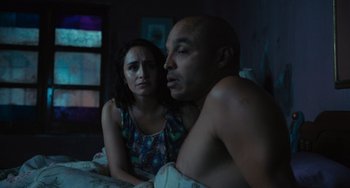 Movie still from “Blue Miracle” (2021), directed by Julio Quintana – A man and a woman sitting on a bed; Medium shot, Over the shoulder angle