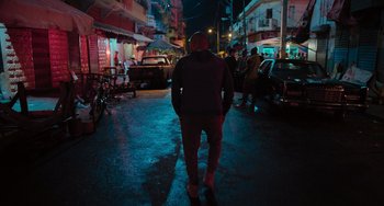 Movie still from “Blue Miracle” (2021), directed by Julio Quintana – A man standing on the side of a street at night; Wide shot, Low angle