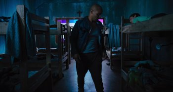 Movie still from “Blue Miracle” (2021), directed by Julio Quintana – A man standing in a room with bunk beds in front of him; Wide shot, Low angle