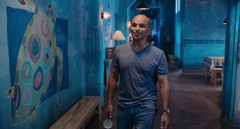 Movie still from “Blue Miracle” (2021), directed by Julio Quintana – A man walking down a hallway holding a cup; Medium shot, Over the shoulder angle