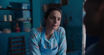 Movie still from “Blue Miracle” (2021), directed by Julio Quintana – A woman sitting in a room wearing an apron; Close Up shot, Low angle