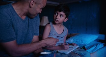 Movie still from “Blue Miracle” (2021), directed by Julio Quintana – A man and a boy sitting on a bed; Medium shot, Over the shoulder angle