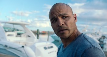 Movie still from “Blue Miracle” (2021), directed by Julio Quintana – A man with a bald head standing in front of a boat; Close Up shot, Low angle