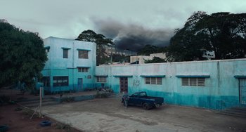 Movie still from “Blue Miracle” (2021), directed by Julio Quintana – A truck parked in front of a blue building; Extreme Wide shot, High angle
