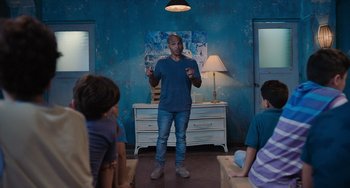 Movie still from “Blue Miracle” (2021), directed by Julio Quintana – A man standing in front of a group of people; Medium shot, Over the shoulder angle