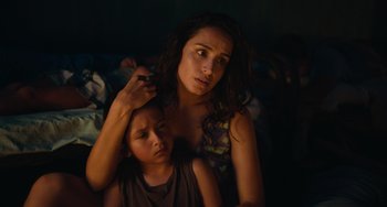 Movie still from “Blue Miracle” (2021), directed by Julio Quintana – A young girl and an older woman in a dark room; Close Up shot, High angle