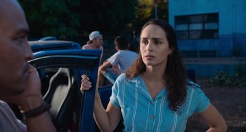 Movie still from “Blue Miracle” (2021), directed by Julio Quintana – A young woman holding onto a car door handle; Close Up shot, Over the shoulder angle