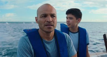 Movie still from “Blue Miracle” (2021), directed by Julio Quintana – A man and a young boy in life jackets on a boat; Close Up shot, Over the shoulder angle