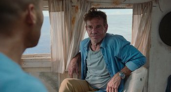 Movie still from “Blue Miracle” (2021), directed by Julio Quintana – A man sitting on a chair in front of a window; Medium shot, Over the shoulder angle
