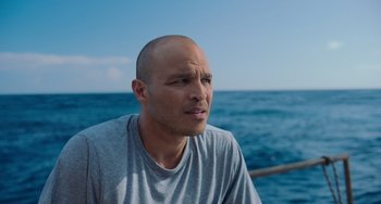 Movie still from “Blue Miracle” (2021), directed by Julio Quintana – A bald man is looking out at the ocean; Close Up shot, High angle