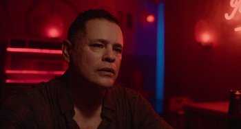 Movie still from “Blue Miracle” (2021), directed by Julio Quintana – A man sitting in front of a red light; Close Up shot, Low angle