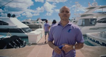Movie still from “Blue Miracle” (2021), directed by Julio Quintana – A man in a purple shirt is standing in front of boats; Medium shot, Low angle