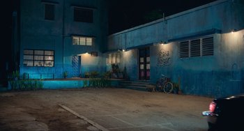 Movie still from “Blue Miracle” (2021), directed by Julio Quintana – A bicycle parked in front of a building at night; Extreme Wide shot, Low angle