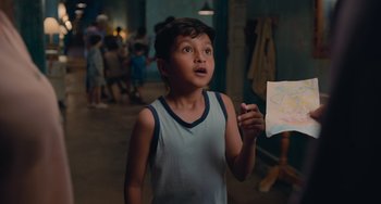 Movie still from “Blue Miracle” (2021), directed by Julio Quintana – A young boy holding a piece of paper in his hand; Medium shot, Over the shoulder angle