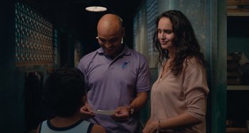 Movie still from “Blue Miracle” (2021), directed by Julio Quintana – A man and a woman standing next to each other holding papers; Medium shot, Over the shoulder angle