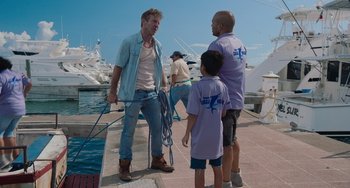 Movie still from “Blue Miracle” (2021), directed by Julio Quintana – A man standing next to two other men near a body of water; Medium shot, Over the shoulder angle