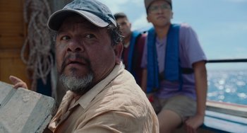 Movie still from “Blue Miracle” (2021), directed by Julio Quintana – A group of men sitting next to each other on a bench; Close Up shot, Over the shoulder angle