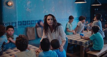 Movie still from “Blue Miracle” (2021), directed by Julio Quintana – A group of people sitting around a table; Medium shot, Over the shoulder angle