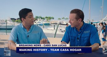 Movie still from “Blue Miracle” (2021), directed by Julio Quintana – Two men sitting in front of each other in front of palm trees; Medium shot, Over the shoulder angle
