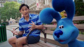 A man sitting on a bench next to a blue dog