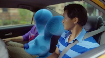 Movie still from “Blue's Big City Adventure” (2022), directed by Matt Stawski – A woman sitting in the back of a car with a stuffed animal; Close Up shot, Over the shoulder angle