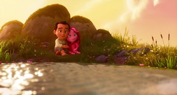 Movie still from “Blush” (2021), directed by Joe Mateo – A boy sitting next to a pink dog in a field; Wide shot, High angle